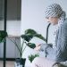 Woman in headscarf sitting indoors, taking medication, symbolizing cancer care and support.